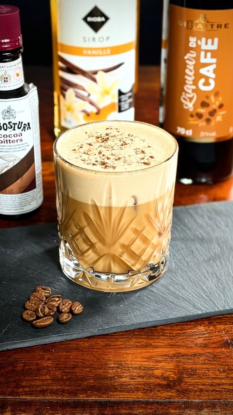 Cocktail crémeux café-vanille saupoudré de cacao, grains de café sur l’ardoise