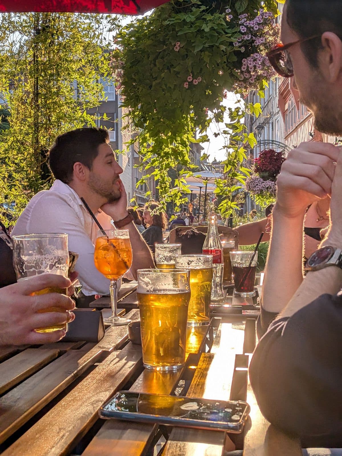 Tablée sous les jardinières fleuries de la terrasse, spritz et pintes